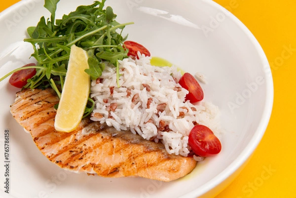 Obraz Salmon steak and rice in a plate on a yellow background.