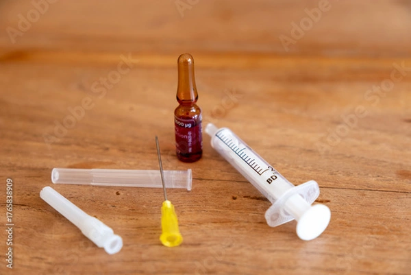 Fototapeta Impfstofffläschchen und Injektionsspritze auf Holztisch