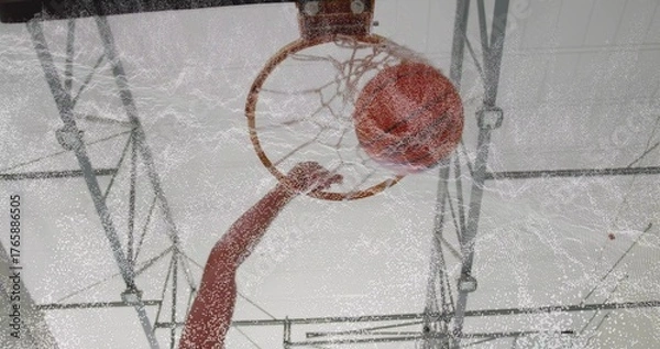 Fototapeta Basketball hoop and net catching basketball passing through in gym with metal trusses, roof panels