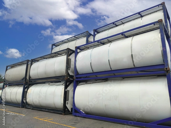 Obraz Isotank container stack in an logistic freight area, showing rows of stainless steel tanks arranged in layers for chemical and liquid transport logistics. 