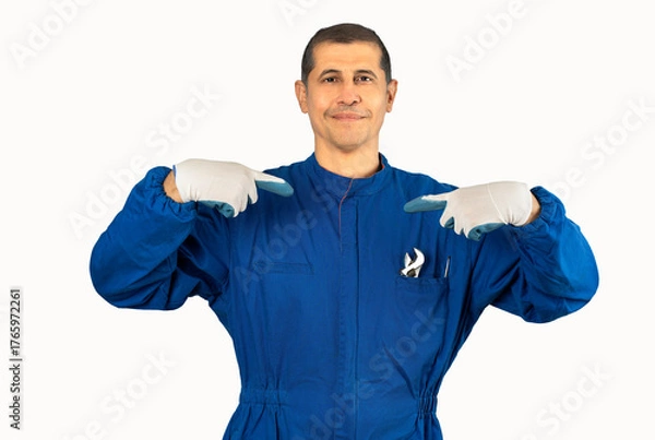Fototapeta Middle age handsome man wearing mechanic blue uniform looking confident with smile on face, pointing oneself with fingers proud and happy