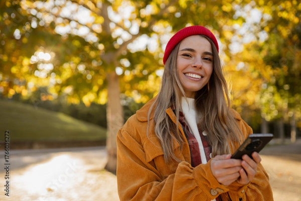 Obraz young attractive blond woman walking in autumn park, stylish , smiling, using smartphone