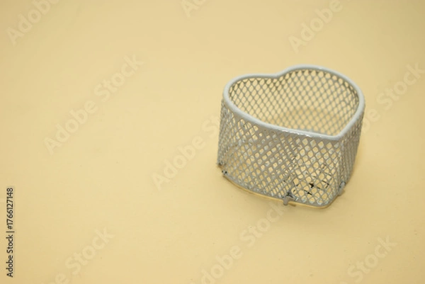 Obraz Empty heart-shaped metal basket on beige surface