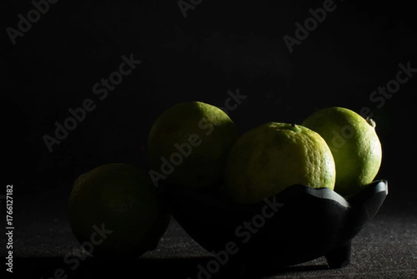 Obraz Bowl of green limes in shadow light
