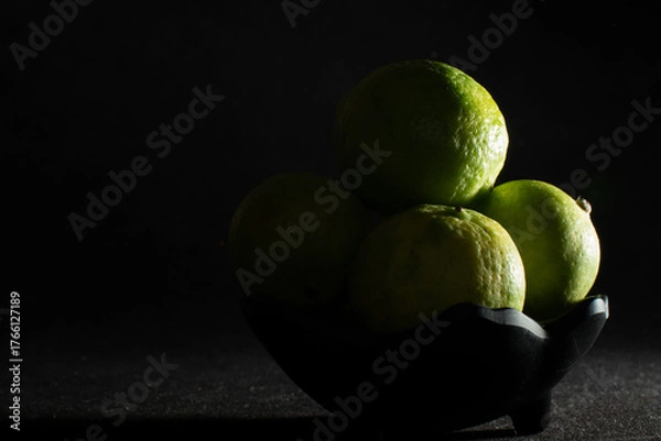 Obraz Bowl of green limes in shadow light