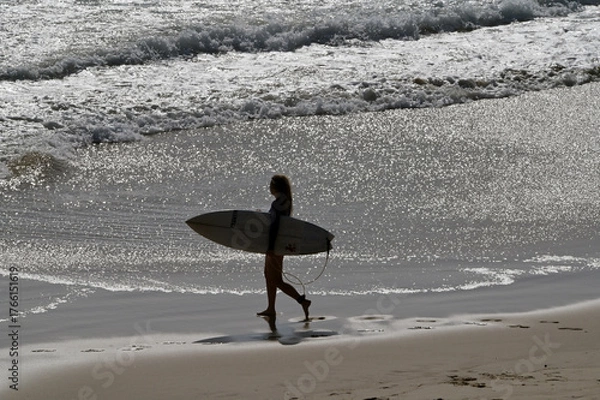 Fototapeta Aerial view of unrecognizable female wave surfer holding a surfing board walking into the sea