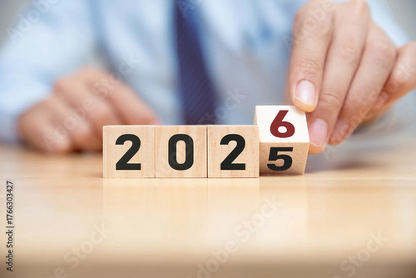 Fototapeta Hand of man flip wooden cube from 2025 to 2026.