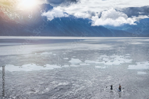 Fototapeta A couple is doing a paddle board in the lake in Alaska,the way to Seward.