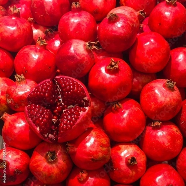 Fototapeta Vivid close-up of ripe, red fruit with one halved, revealing jewel-like seeds