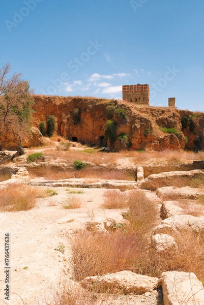 Fototapeta Distant view of a rocky hilltop in Fes, Morocco, featuring an ancient ruined wall and dry desert landscape under clear blue sky.