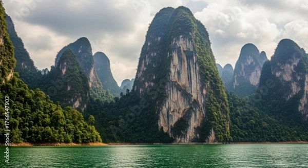 Fototapeta Majestic limestone cliffs covered in lush green vegetation rising from the tranquil waters