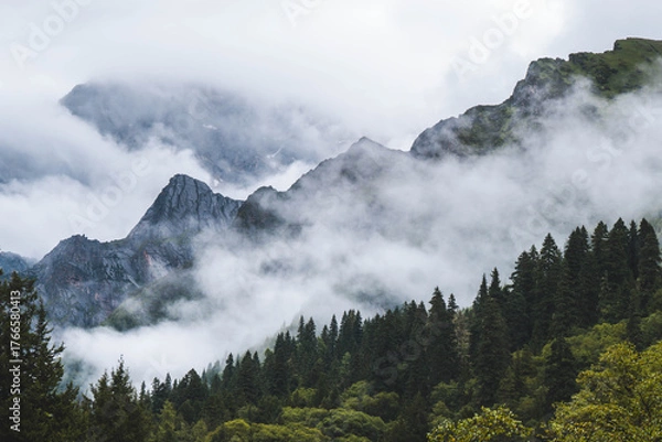 Fototapeta Beautiful view mountain with mist on the sky, snow mountain, peak of mountain and some clouds at Changpinggou Trail, Four Girl Mountain, Sichuan of China. color effect, low key and soft focus.