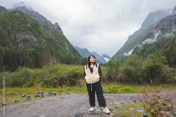 Fototapeta happy woman tourist trekking at mountain in Changping valley near Siguniang mountain in Sichuan province, China, color effect, low key and soft focus.