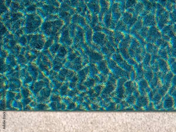 Fototapeta Ripples reflecting sunlight from the clear water in the swimming pool