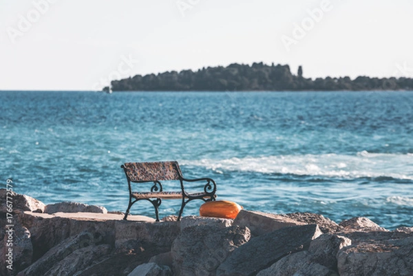 Fototapeta bench by the sea under pale, golden light and the istrian panorama
