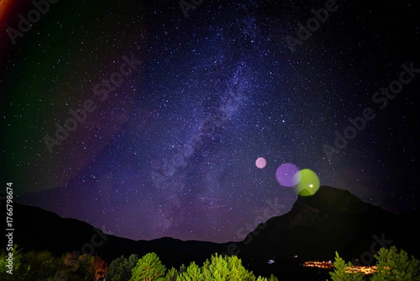 Obraz Breathtaking night sky panorama showcases the Milky Way galaxy over silhouetted mountains and vibrant trees, inspiring wonder and awe.