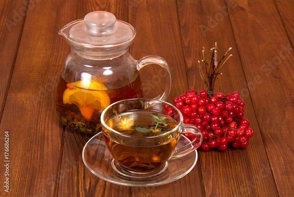 Fototapeta A jug with hot tea and bunch of viburnum from colds, on wooden table