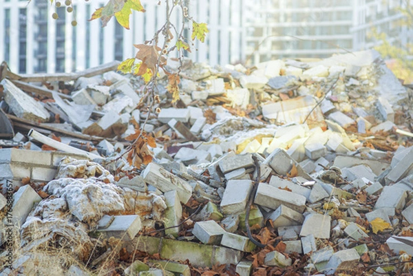 Fototapeta View of demolished building fragments illuminated by rays of sun. Concepts of construction waste challenge, demolition site ecology, circular economy opportunity, and building material recovery. 