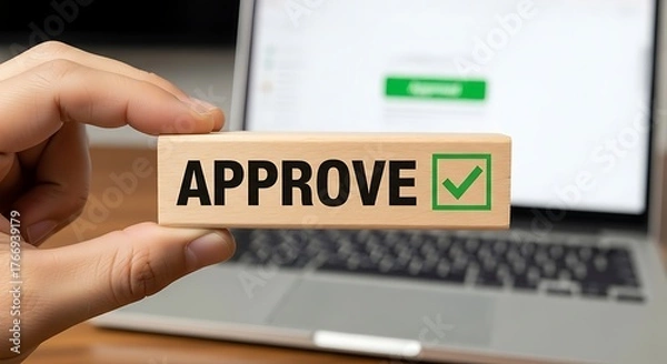 Obraz Hand holding wooden block with approve text and checkmark in front of laptop approval agreement