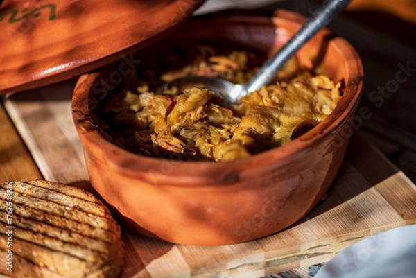 Fototapeta A bowl of cooked cabbage served in a rustic brown dish, showcasing its soft texture and warm, comforting appearance. The natural colors and simple presentation make this image suitable for traditional