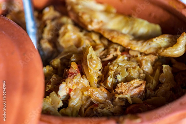 Fototapeta A bowl of cooked cabbage served in a rustic brown dish, showcasing its soft texture and warm, comforting appearance. The natural colors and simple presentation make this image suitable for traditional