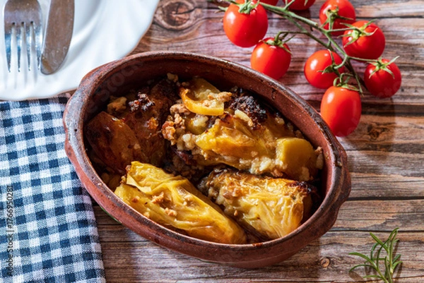 Fototapeta Traditional cabbage rolls (sarma) served in a rustic brown bowl, showcasing tender leaves stuffed with a savory meat and rice filling. The warm, hearty dish is highlighted by natural lighting, emphasi