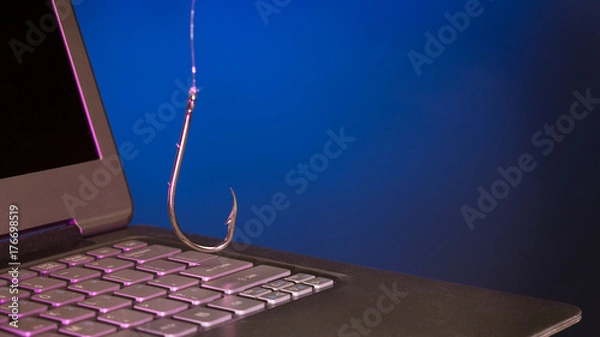 Obraz fish hook hanging above a laptop keyboard