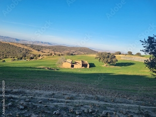 Fototapeta An old mud hut in the middle of nature and green plains in the mountainous countryside