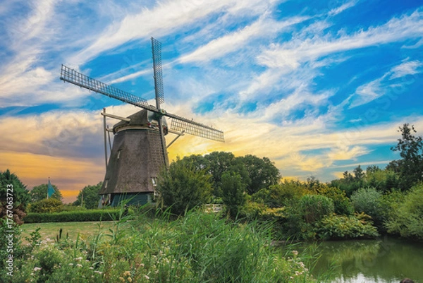 Fototapeta Old Dutch windmill in the Netherlands, traditional mill with a beautiful view of a clear, cloudy sky