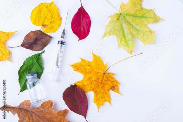 Fototapeta Autumn vaccination of population. Syringe in autumn leaves. Vaccination in autumn. New vaccine..