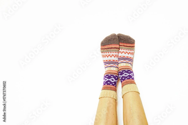 Obraz Warm patterned socks on relaxed feet over white background. Symbol of domestic tranquility and slow mornings. Relates to sustainable fashion, ethical design, and seasonal warmth during cold months.