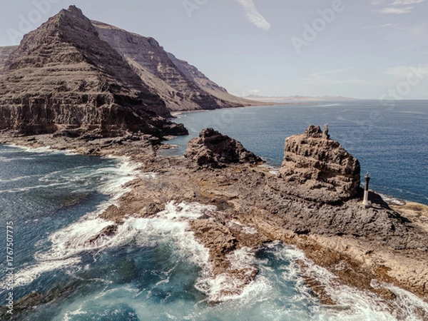 Fototapeta Aerial view of rugged volcanic cliffs and rock formations near Orzola, Lanzarote, surrounded by turquoise Atlantic waters.  
