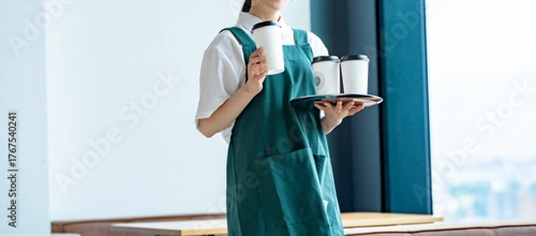 Obraz コーヒーカップを持つエプロンをつけた女性カフェスタッフ