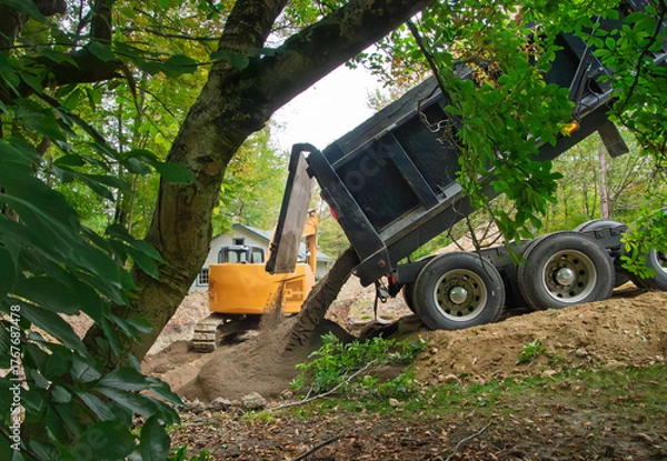 Fototapeta A dump truck dumping a load of sand into an excavation for a home septic system waste field