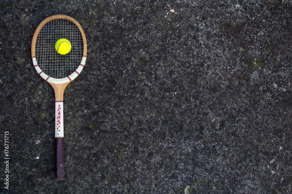 Obraz Old vintage wooden tennis racket on isolated stone background with green ball.