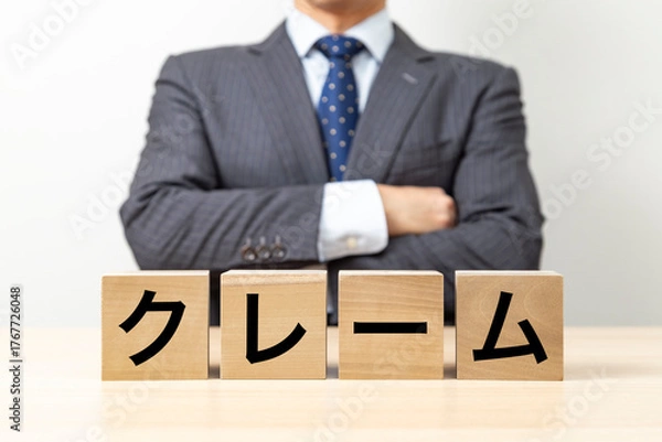Obraz 「クレーム」と書かれたブロックと腕組みをするビジネスマン