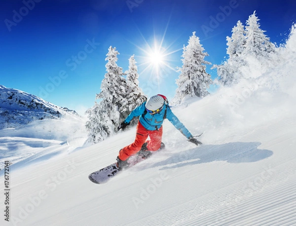 Fototapeta Snowboardzista młody człowiek zbiegający ze stoku w alpejskich górach