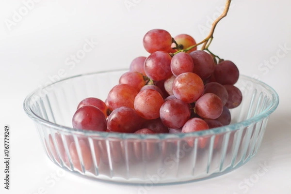 Fototapeta Red table grapes in a clear glass bowl, featuring Red Globe, Crimson Seedless, or Flame Seedless