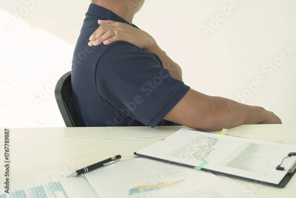Fototapeta An asian businessman having tensed muscles fatigued, neck, shoulder, back pain during work long time in office, due to fibromyalgia, rheumatism, scapular pain, office syndrome and ergonomic concept.