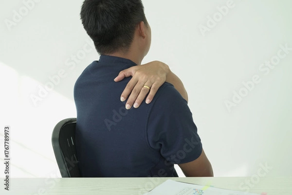 Fototapeta An asian businessman having tensed muscles fatigued, neck, shoulder, back pain during work long time in office, due to fibromyalgia, rheumatism, scapular pain, office syndrome and ergonomic concept.