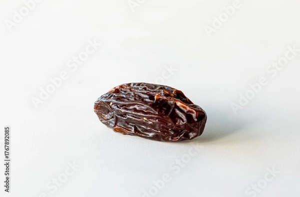 Fototapeta A single whole medjool date isolated against a white background.