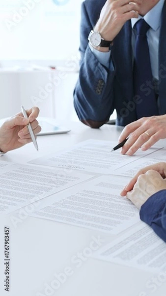 Fototapeta Business colleagues reviewing contract documents during an office meeting, discussing terms, and preparing for agreement signing, focusing on legal consultation and partnership discussion
