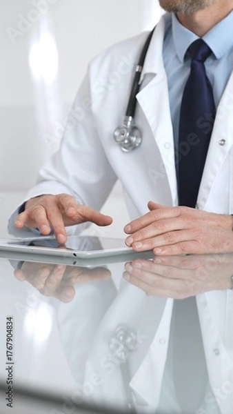 Fototapeta Doctor using digital tablet, consulting with patient, working in healthcare office, telemedicine and medical technology concept. Medicine and health care