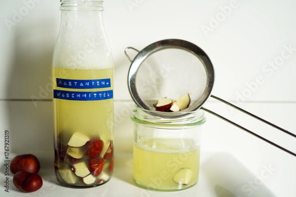 Fototapeta Natural detergent prepared from horse chestnuts in a clear glass bottle with light brown liquid. German text on the label indicates natural, eco-conscious living.