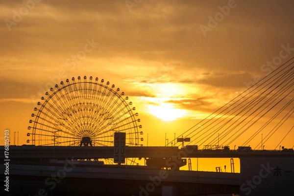 Fototapeta 夕陽に染まる観覧車と橋を渡る車のシルエット