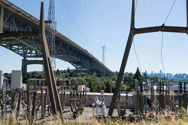 Fototapeta Low angle view of freeway bridge, specifically the the Ship Canal Bridge/I-5, as seen from behind transformer station. Taken while walking in the Seattle urban area on a clear July day.