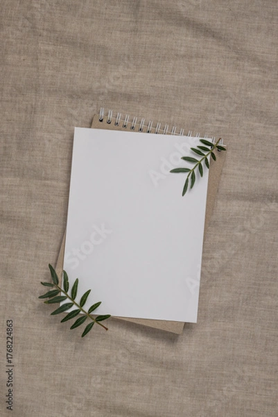 Fototapeta Summer wedding stationery mock-up scene. Blank greeting card, craft paper envelope and green branches on linen textile background.