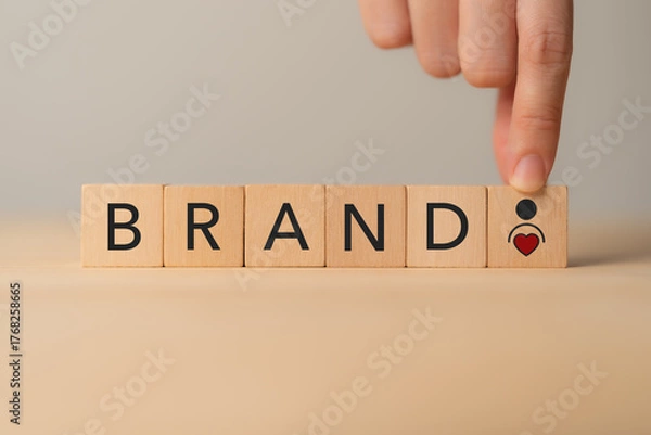 Fototapeta Building brand with customer loyalty concept. Wooden blocks spelling “BRAND,” and a heart and person icon. Brand building, trust and customer loyalty.