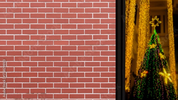 Fototapeta Beautiful old brown brick wall with blurred bokeh from brightness Chrismas tree outside clear window. 16:9 copy space format.