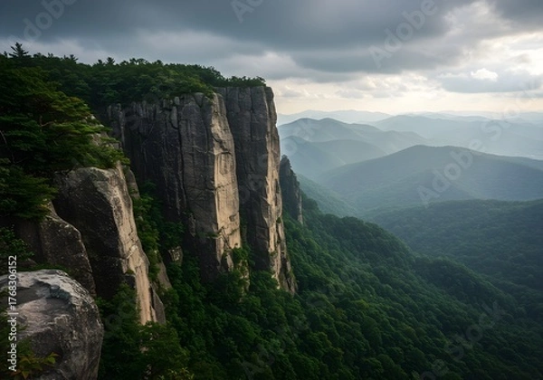 Fototapeta Dramatic Cliffs Overlooking Misty Mountain Range at Dusk